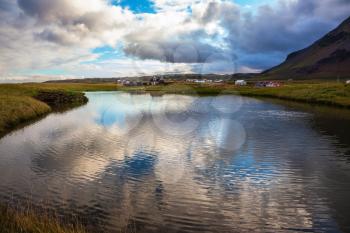 Small pond in the fishing settlement of Arnastapi. Quiet summer evening on the coast of Iceland