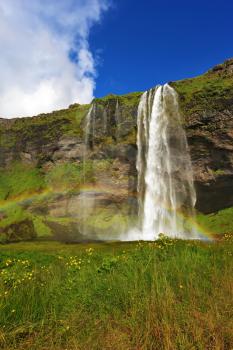  Sunny day in July. Seljalandsfoss waterfall in Iceland. Large rainbow decorates a drop of water