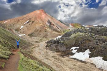 The famous Valley Landmannalaugar. Delighted woman - tourist lifted her hands, unable to cope with emotions