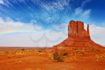  Famous rock - mitts of red sandstone. In the sky a rainbow. Magical landscape Monument Valley in Arizona