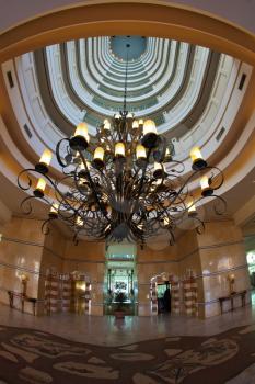 Magnificent hall of dear hotel. A huge luster on a metal circuit, lifts and marble floors