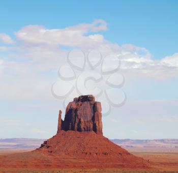 The famous Mittens in Monument Valley. The cliffs of red sandstone on the background of the cloudy sky