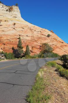A bright sunny day in Zion National Park. Excellent road winds sharply between the picturesque hills of colorful striped sandstone
