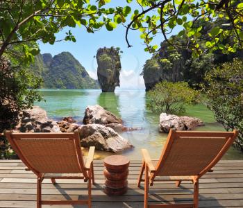  Beautiful scenery in the world. The island in the shape of a green vase in the sea bay with pure emerald water. The comfortable place to enjoy the beauty of the landscape. Two wooden chairs - on a wo