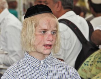 JERUSALEM, ISRAEL - SEPTEMBER 18, 2013: Big market on the eve of the Jewish holiday of Sukkot. The boy - teenager with long blond hair and a black velvet skullcap 