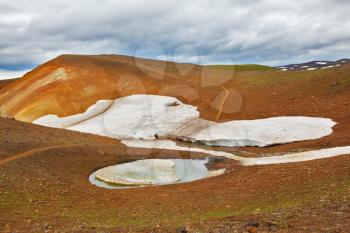 July in Iceland. Smoldering underground heat hillsides. In the hollows are last year's snow fields