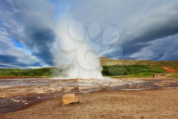 Iceland in the summer. Gushing geyser Strokkur. High column of hot water and steam from the crater of the geyser. 