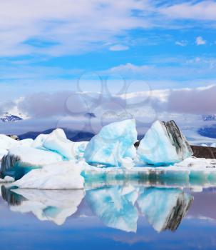 Icebergs and ice floes are reflected in smooth water. Iceland in July. Ocean ice lagoon Jökulsárlón