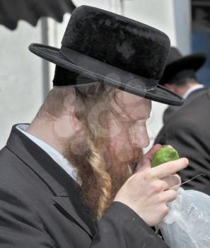 JERUSALEM, ISRAEL - SEPTEMBER 18, 2013: Traditional market before the holiday of Sukkot. The religious Jew with red beard and long sidelocks inspects ritual citrus