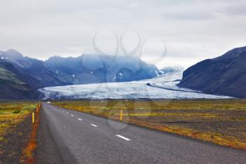 Highway next to  huge glacier in the mountains of Iceland. Summer in the north