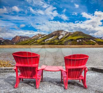 Two comfortable red deck chairs are for rest.  Valley among the rhyolite mountains and shallow streams