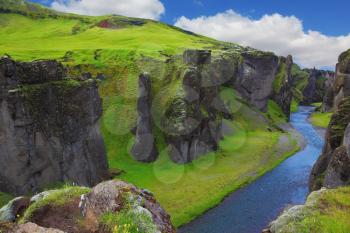 Dreamland Iceland. The picturesque canyon  Fjadrargljufur, green grass of rocks and blue ribbon of the river