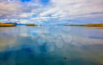 Cold summer in Iceland. Smooth water of the cold fjord reflects clouds