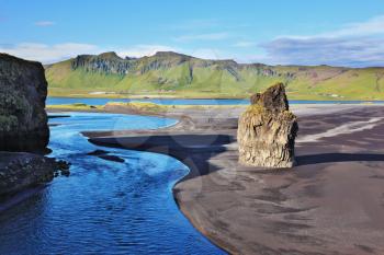 Rock in the sand. Cape Dirholaey in southern Iceland. On the beach with black volcanic sand is a huge rock 