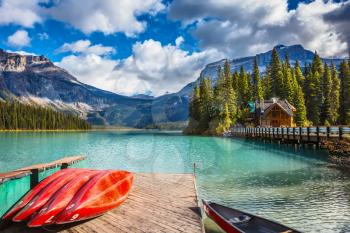 Brilliant red kayaks dry upside down. Emerald Lake in Canadian Rockies. Concept of active vacation and tourism