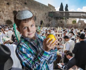  Charming seven year old boy in white festive skullcap with etrog. Sukkot at the Western Wall of Temple in Jerusalem