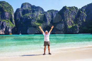 Cheerful elderly man standing in the water on Phi Phi island in Thailand