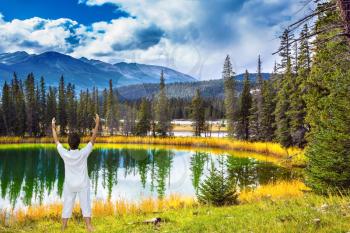 Woman, dressed for yoga, Sun Salutation on the bank of round lake. Jasper National Park in the Rocky Mountains. Patricia Lake