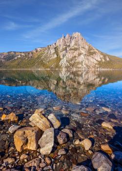 Picturesque mountain in the city of San Carlos de Bariloche, Argentina. The mirror water of shallow lake reflects sharp peaks and rocks. The concept of exotic and extreme tourism