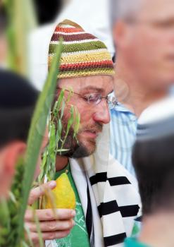 JERUSALEM, ISRAEL - SEPTEMBER 20, 2013:  Young religious Jew in a knitted skullcap and talite with citrus-etrog praying in the morning of Sukkot. The Western Wall of the Temple in Jerusalem