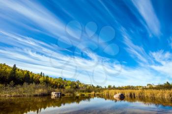Indian summer in Manitoba, Canada. Cirrus clouds are reflected in the Winnipeg River. Old Pinawa Dam Park. The concept of ecological and recreational tourism