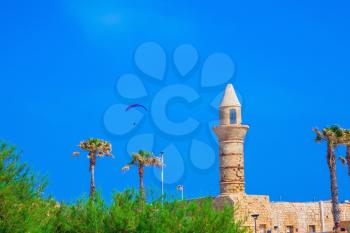 Minaret, walls and palm Arab period Caesarea. In the blue sky flying controllable parachute.  National park Caesarea 