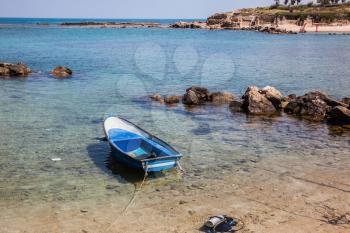 The shallow bay and blue fishing boat, moored near the shore. Next to the boat - diving equipment