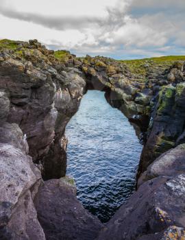 The picturesque arch in the rocks near the fishing village of Arnastapi. Iceland in July