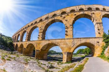 Three-tiered aqueduct bridge Pont du Gard was built in Roman times on the river Gardon. Provence sunset. Photo taken fisheye lens