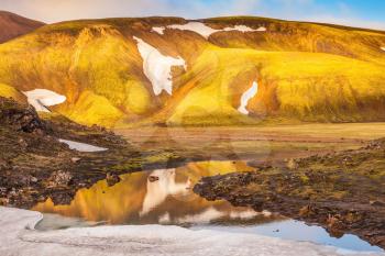 Light golden dawn illuminates the mountains and glaciers . The  sunrise in national park Landmannalaugar, Iceland