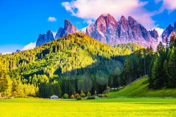  The sun illuminates grandiose gear rocks of Tirol. Small picturesque village in Alpine meadows. The Dolomites. The concept of eco-tourism