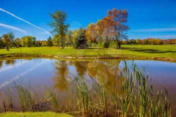 Shining sunny day in French Canada. Red and green autumn foliage reflected in small pond with clay bottom. Concept of recreational tourism