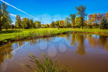  Red and green autumn foliage reflected in small pond with clay bottom. Shining sunny day in French Canada. Concept of recreational tourism