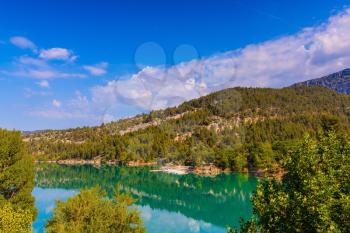 Smooth emerald river water reflects the sky and wooded shore. Mountain canyon Verdon in the French Alps