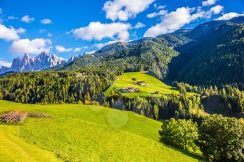 Charming chalet on a green grassy slope. The valley is surrounded by dolomite rocks. Warm autumn in the Dolomites. The concept of ecological tourism