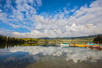 Cumulus clouds over the Pyramid mountain and Pyramid Lake. Wooden boat dock with moored pleasure boats 