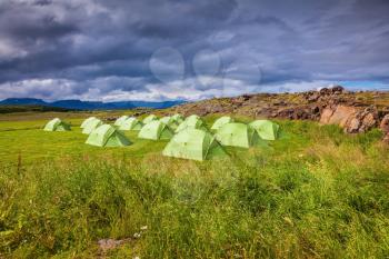 Campground in Iceland. Green tent on a grassy lawn. July in the Arctic