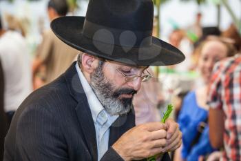 JERUSALEM, ISRAEL - OKTOBER 8, 2014: Traditional market before the holiday of Sukkot. Orthodox men with a white beard in black hat chooses citrus - etrog