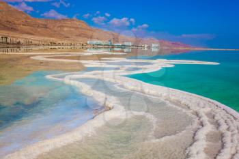 Dead Sea, Israel. Reduced water in the very salty Dead Sea. The evaporated salt is precipitated by picturesque stripes in shallow water. The concept of medical and ecological tourism. 