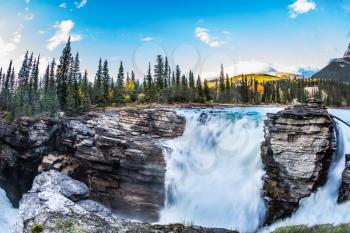 Travel to Jasper Park, Canada. The waters of a melting mountain glacier feed the seething waterfall of Athabasca. The concept of ecological tourism