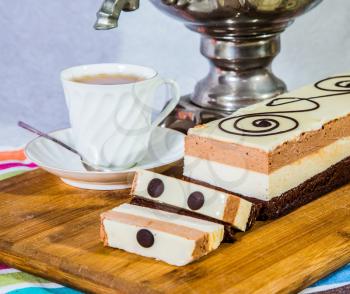 Gorgeous holiday cake Three-colate. The background is shiny samovar and porcelain cup with tea. Professional bakery. Three-layered chocolate cake decorated with chocolate patterns 