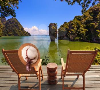 Exotic rest in Thailand. The coast of the gulf in the Andaman Sea. Two convenient chaise lounges and an elegant hat on one