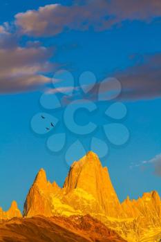 Fiery sunset illuminates the majestic mountains - rocks Fitz Roy. Thd stunning Patagonia