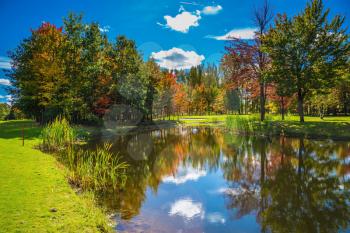  Red and green autumn foliage is reflected to clear water of the lake. Very nice park. Golf Club on the road to Bromont, French Canada. Concept of Golf tourism