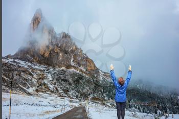  Dolomites in Northern Italy. First snow on mountain passes Giau. Elderly woman in awe of the beauty of nature