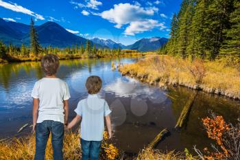 Two little boys holding hands on the lake.  Indian summer in the Rocky Mountains of Canada. Concept of ecological tourism