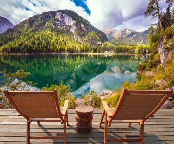 Pair of sun loungers on the lake. Magnificent lake in South Tyrol, Italy. The concept of walking and eco-tourism. Water reflects the surrounding mountains and forest
