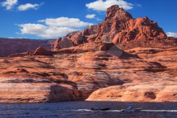 Picturesque artificial huge reservoir Powell on the river Colorado, USA. The lake is surrounded with picturesque coast from orange sandstone. Walk on the lake Powell on a sunset