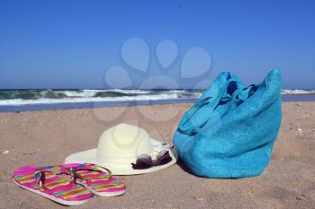 Summer concept with bag, hat, sun glasses and flip flops on beach