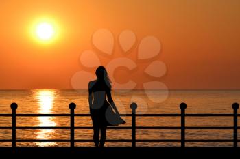 Woman silhouette enjoying sunrise on the waterfront 